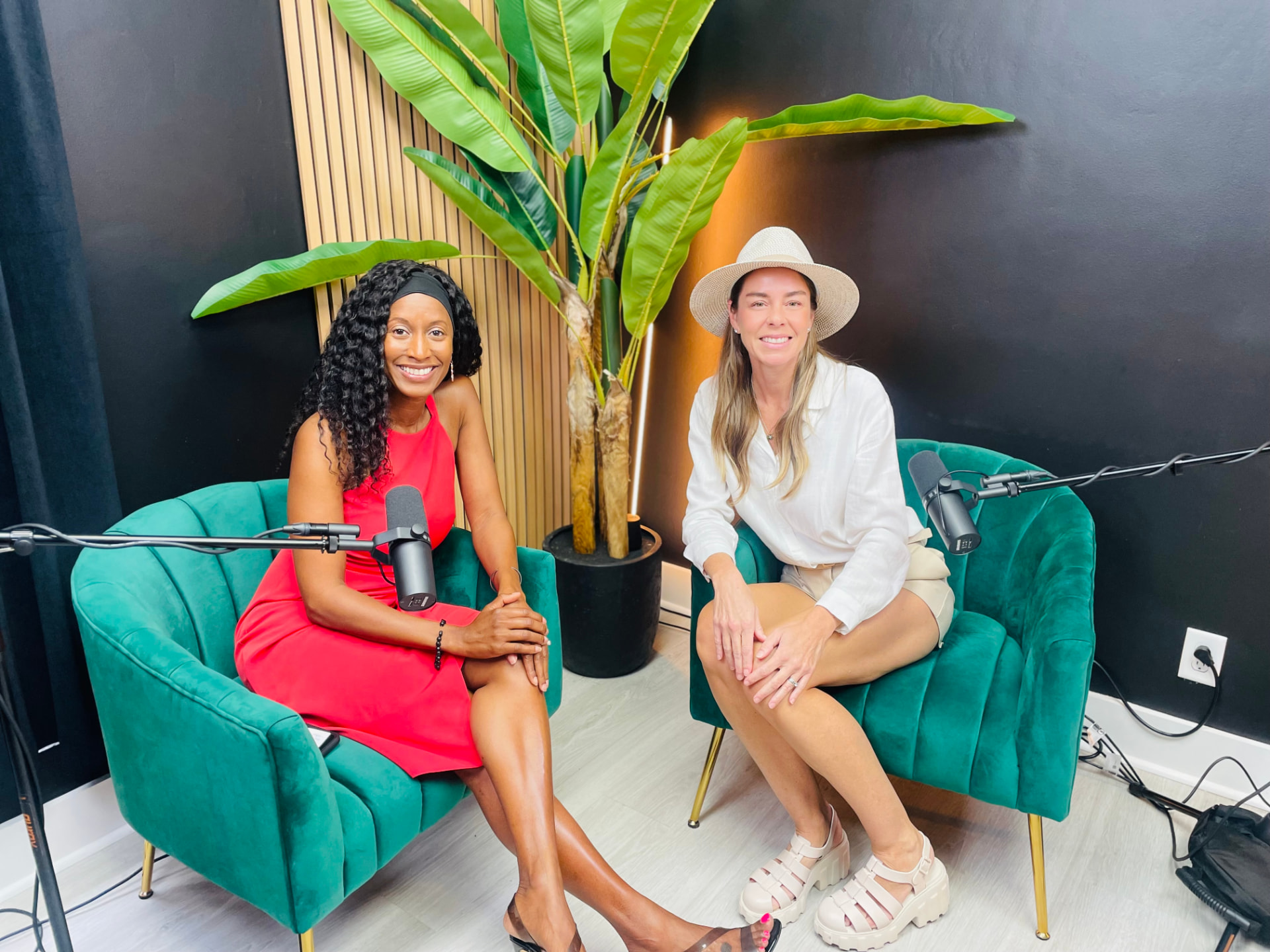 Two HBN members smiling in green armchairs during a podcast interview